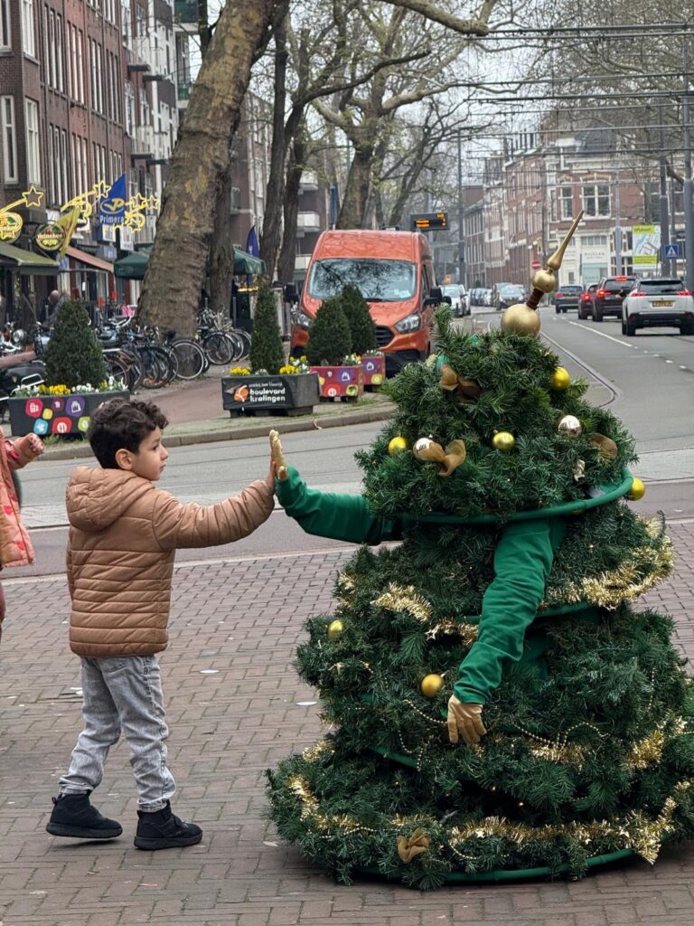 Kind begroet persoon verkleed als kerstboom op straat